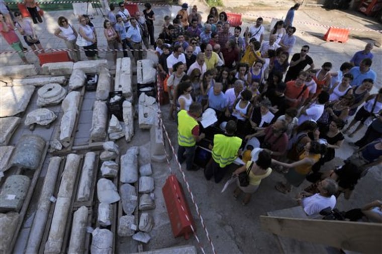 Archaeologists and employees of Metro's construction company present to the media and public the ancient ruins in the northern Greek port city of Thessaloniki on Monday, June 25, 2012. Archaeologists in Greece’s second largest city have uncovered a 70-meter (230-foot) section of an ancient road built by the Romans that was city’s main travel artery nearly 2,000 years ago. The marble-paved road was unearthed during excavations for the city’s new subway system that is due to be completed in four years, and will be raised to be put on permanent display for passengers when the metro opens. (AP Photo/Nikolas Giakoumidis)